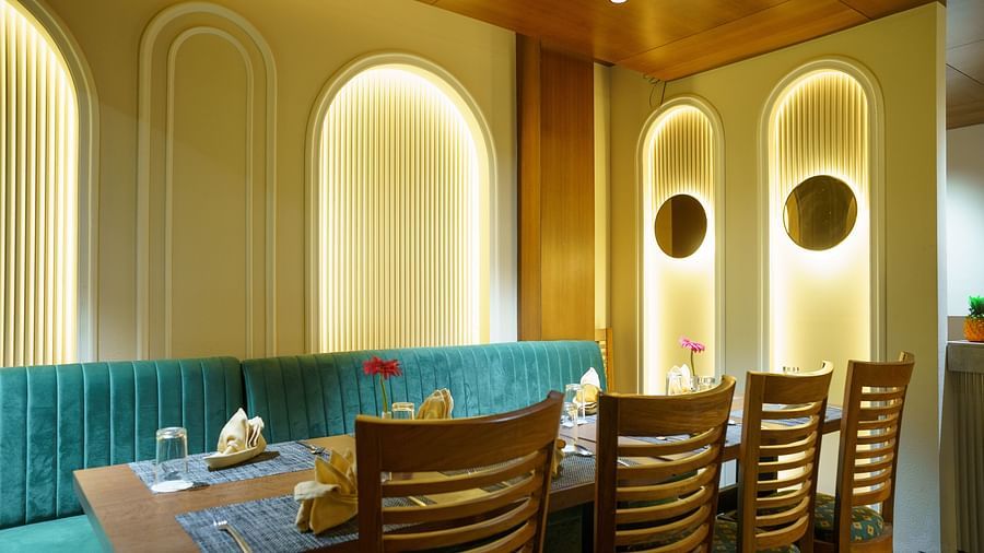 A wide shot of a dining area with booths featuring turquoise upholstery and wooden tables at Orsino Spa Resort.