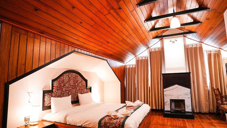 A room at Orsino Spa Resort with a wooden ceiling, featuring a bed with white linen and a red bed runner, and wooden panelling.