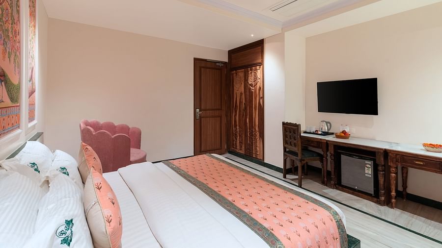 A spacious bedroom view from the headboard at Panna Vilas Palace, showcasing a wall-mounted television with a wooden table positioned below it | Panna Vilas Udaipur