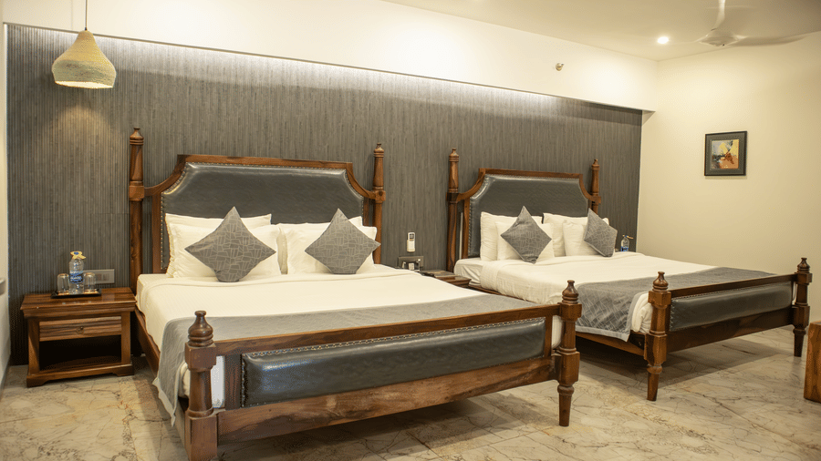 A bedroom setting having modern furnishing with twin beds, side tables, and bright lighting at Club Room of Papaya Tree Hotels.