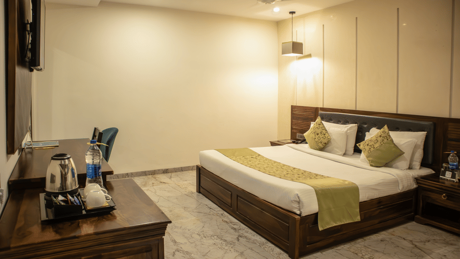 Executive Room of Papaya Tree Hotels with a double bed, an overhead lamp, and simple furnishing with a wooden cabinet.