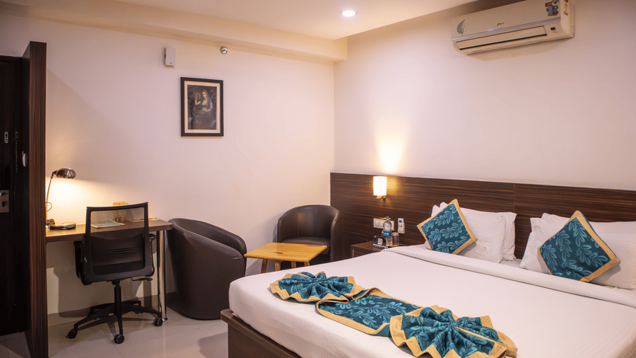 An extended view of a well-furnished Executive room with a large bed, a small seating area with 2 armchairs and a coffee table at Papaya Tree Hotels.