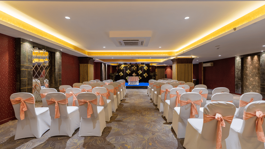 Galaxy Banquet hall at Papaya Tree Hotels arranged with neatly aligned chairs and a stage setup for meetings or formal events.