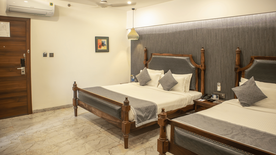 Wide view of a Bedroom at showcasing modern interior with twin beds and a door opening to another room |at Papaya Tree Hotels.