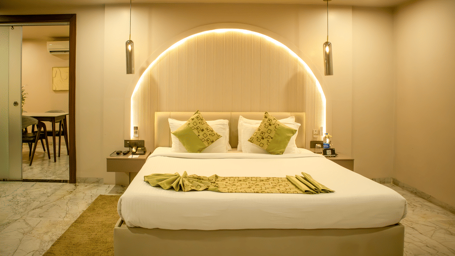 Side view of one of the accommodations at Papaya Tree Hotels showcasing ample lighting, double bed, and a door opening to another room.