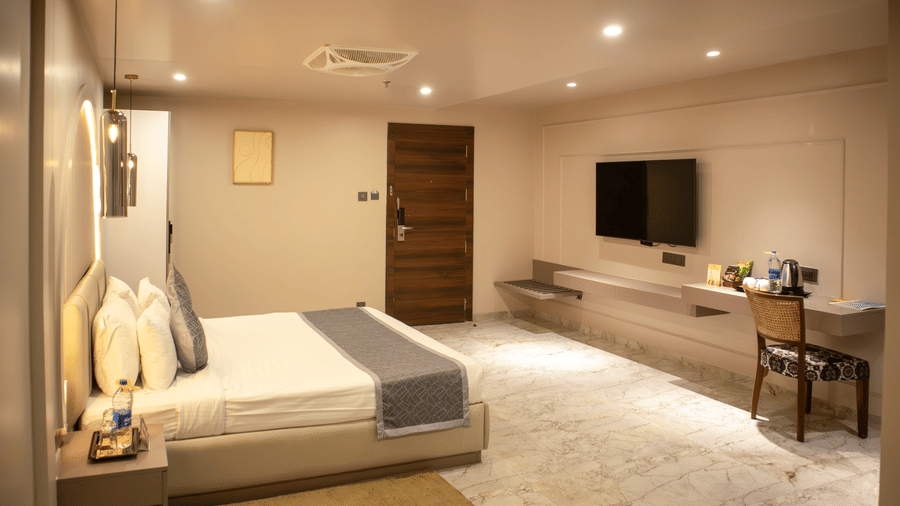 Bedroom of a Suite in Papaya Tree Hotels furnished with cosy bedding, a wall-mounted television, and modern furnishing.