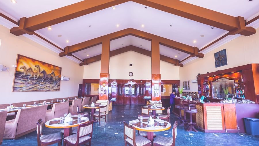 Interiors of a restaurant at Paradise Isle Beach Resort, Udupi with seating arrangement and wooden beams