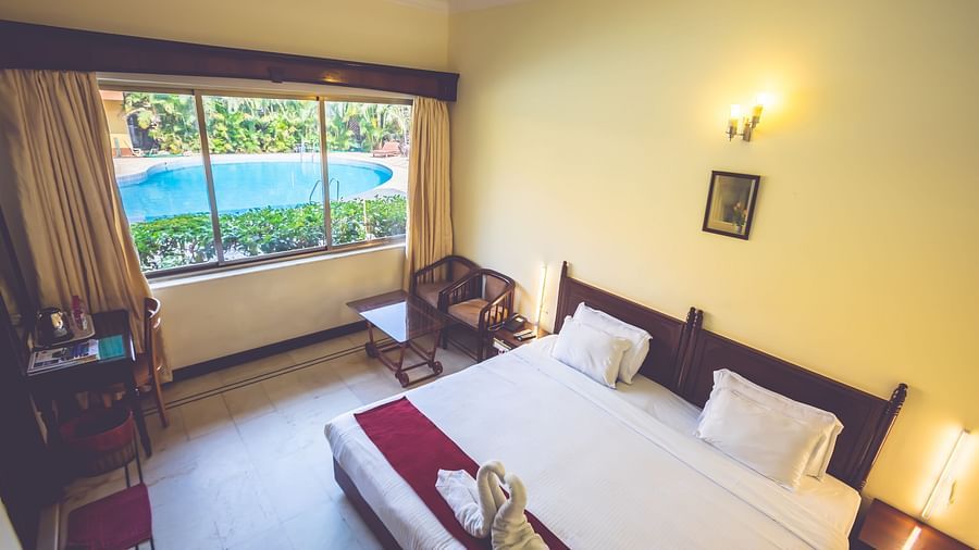 Standard Room at Paradise Isle Beach Resort, Udupi with a double bed and view of the swimming pool from the window