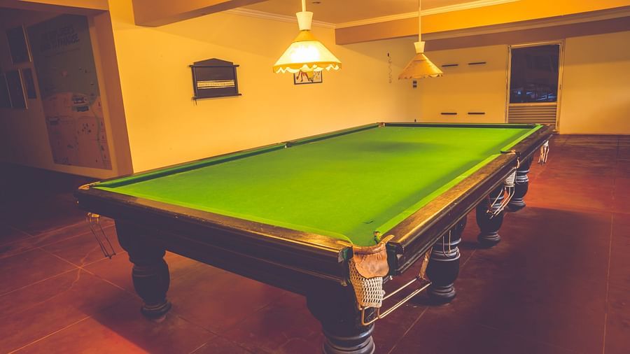A view of a snooker table lit up by warm lights in the gaming room at Paradise Isle Beach Resort, Udupi