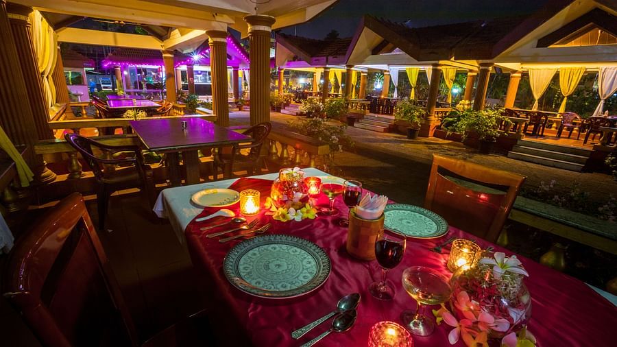 A candle light dining arrangement at Paradise Isle Beach Resort, Udupi with the cottages in the backdrop