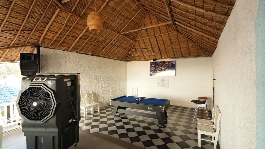 A pool table placed in the centre of a room with a television and a cooler at Paradise Isle Beach Resort, Udupi