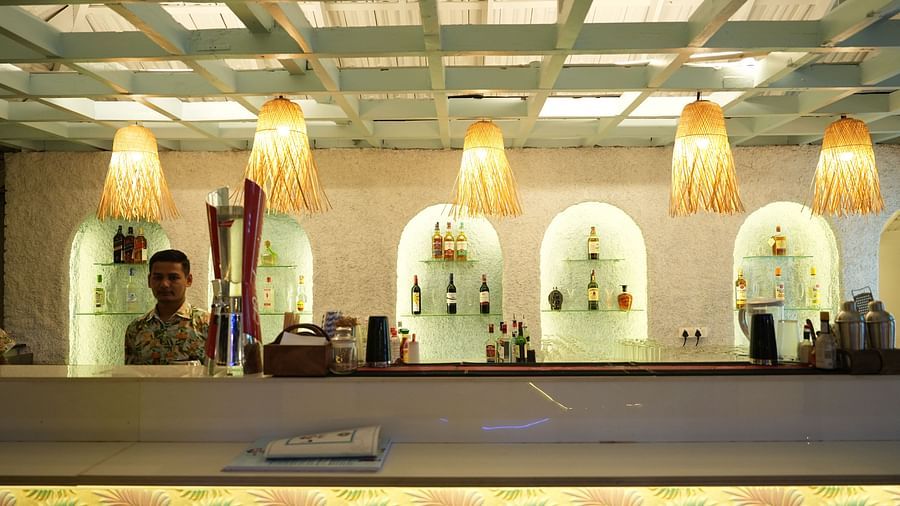 A bar counter in a restaurant at Paradise Isle Beach Resort, Udupi with decorative lights hanging over it