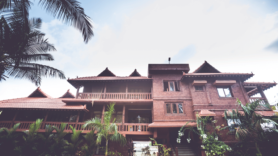 Paradise Lagoon Resort's facade with red-tiled roof, surrounded by palm trees and a driveway.