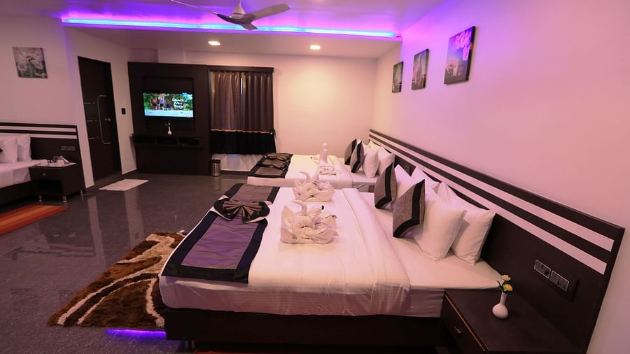 Side view of a room with two beds and a television beside it at Parampara Residency, Kushalnagar.