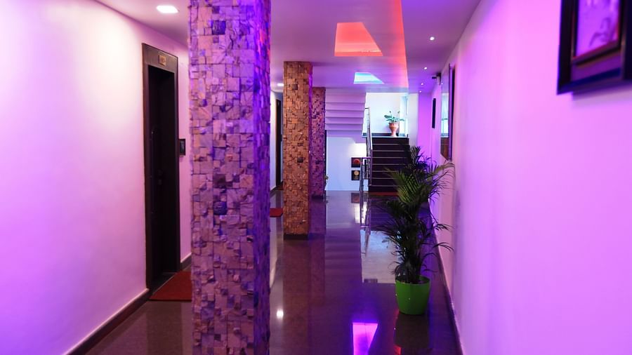 Image of a hallway with pillars in the middle and plants on the side at Parampara Residency, Kushalnagar.