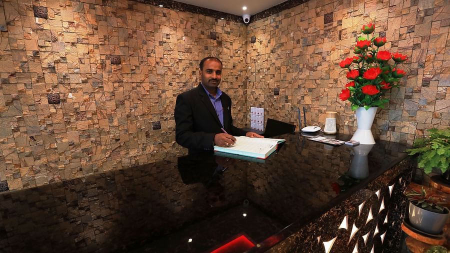 Image of a man standing behind a counter table posing for the lens at Parampara Residency, Kushalnagar.
