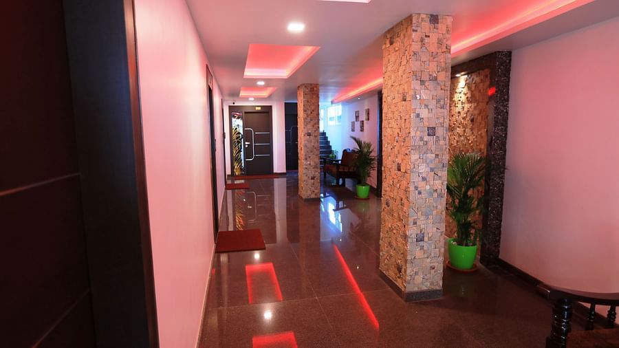 Image of a corridor with doors on the side and lights on the ceiling at Parampara Residency, Kushalnagar..