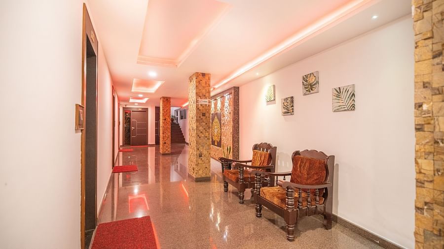 Image of a hallway with two wooden chairs on the side at Parampara Residency, Kushalnagar.
