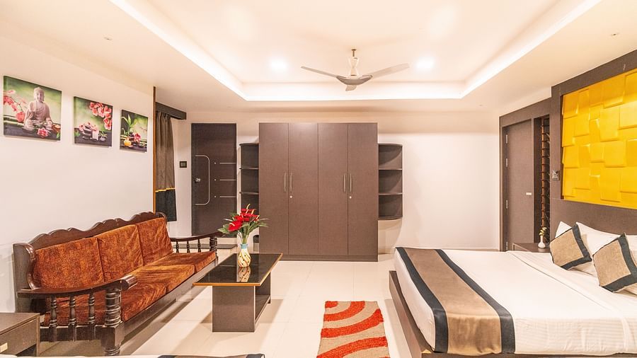 A room with a bed and a sofa in front of it at Parampara Residency, Kushalnagar.
