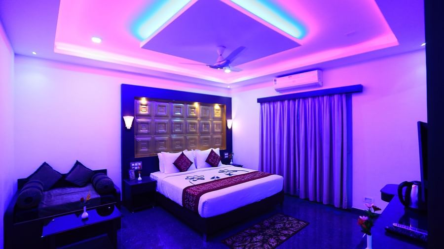 Image of a dimly lit room with a bed and a seating area on the side at Parampara Resort & Spa, Kushalnagar.