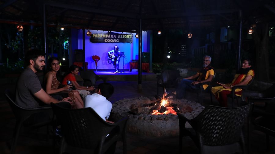 Image of a group of people sitting around a bonfire at Parampara Resort & Spa, Kushalnagar.