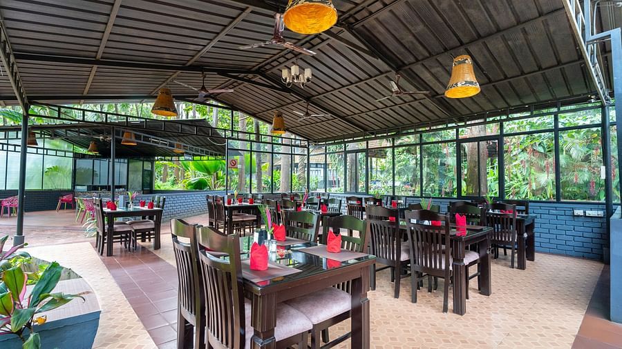 Image of a dining space with tables and chairs and lights hanging from the ceiling at Parampara Resort & Spa, Kushalnagar.