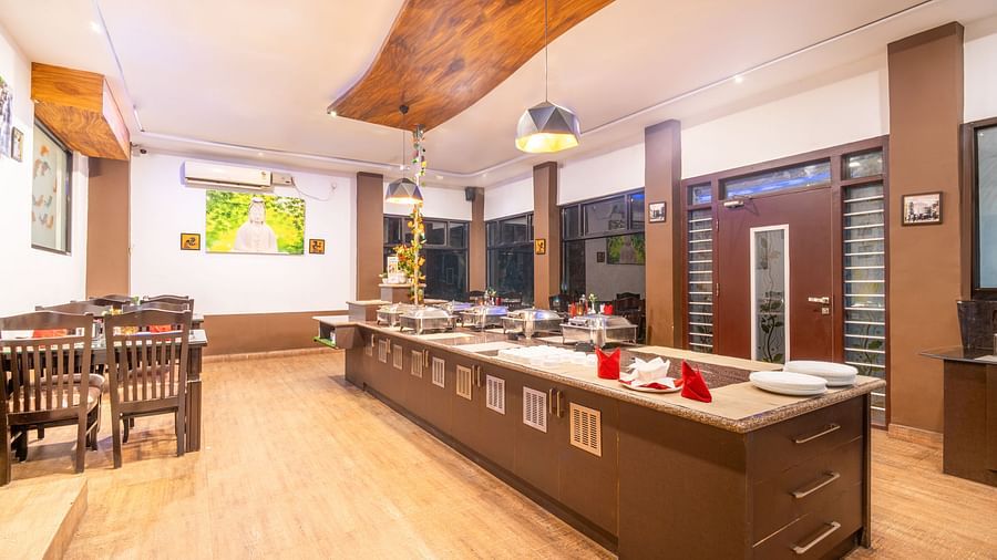 Image of a dining hall with a buffet table with crockery and sitting area on the side at Parampara Resort & Spa, Kushalnagar.