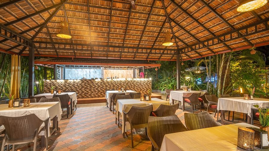 Image of a dining hall with a seating area and a slanted roof at Parampara Resort & Spa, Kushalnagar.
