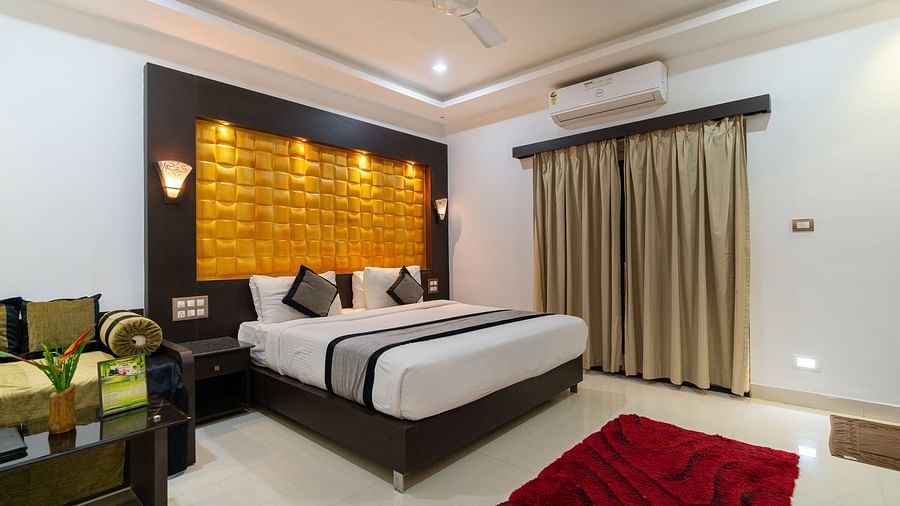 Image of a room with a bed and a sofa and a table on the side at Parampara Resort & Spa, Kushalnagar.