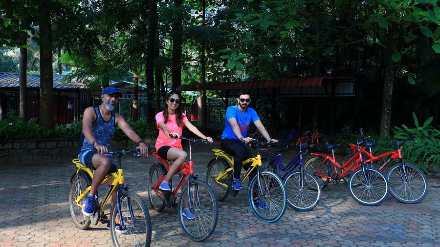 Image of three people on a cycle at Parampara Resort & Spa, Kushalnagar.