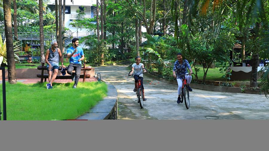 Image of two people cycling and two people watching them at Parampara Resort & Spa, Kushalnagar.