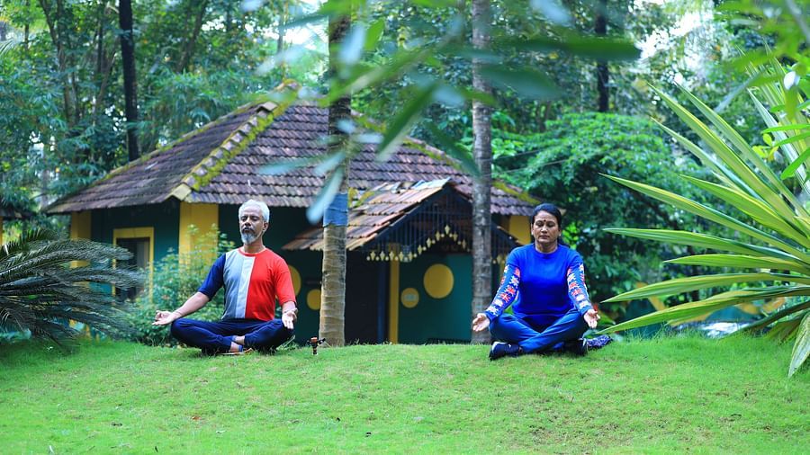 Image of a man and woman sitting on grass surrounded by plants at Parampara Resort & Spa, Kushalnagar.