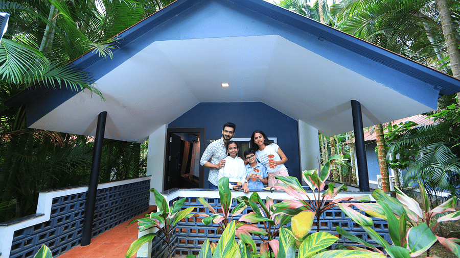 Facade of an accommodation with four people standing in front of it, posing for a photo at Parampara Resort & Spa, Kushalnagar.