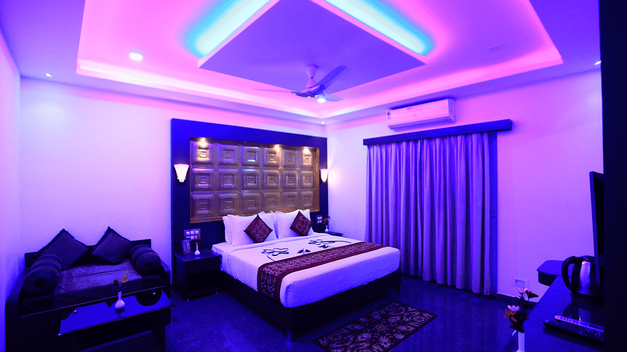 A dimly lit room with a bed and a seating area on the side at Parampara Resort & Spa, Kushalnagar.