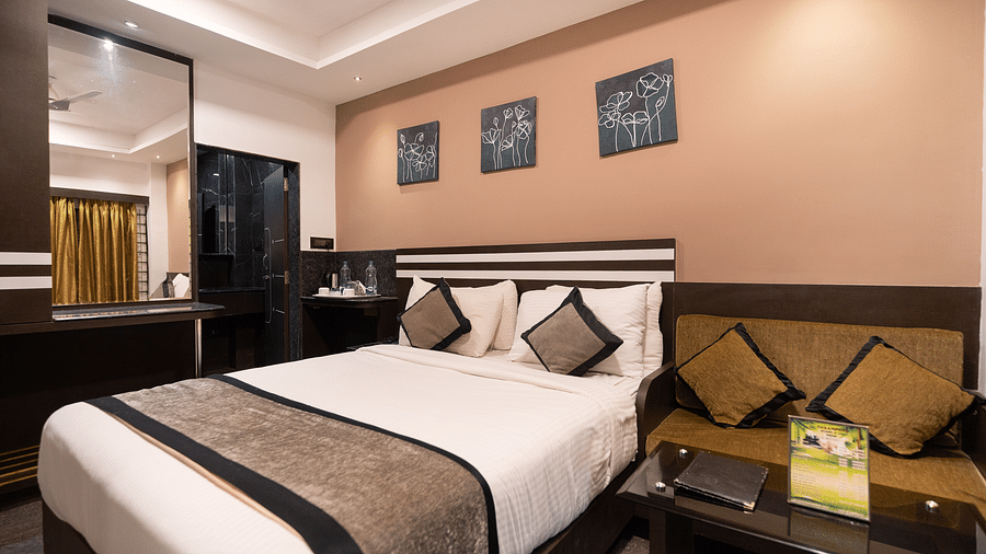 A room with a bed with a mirror on the side at Parampara Resort & Spa, Kushalnagar.
