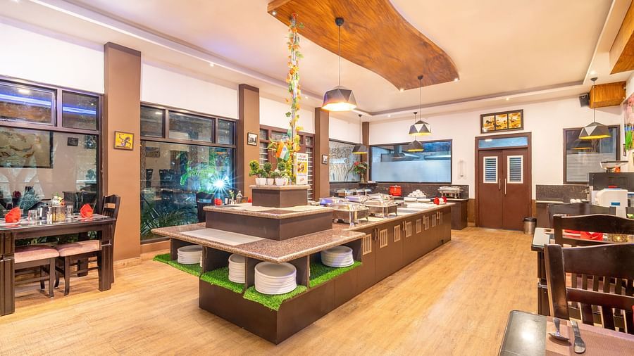 A dining hall with a buffet table and wooden decor at Parampara Resort & Spa, Kushalnagar.