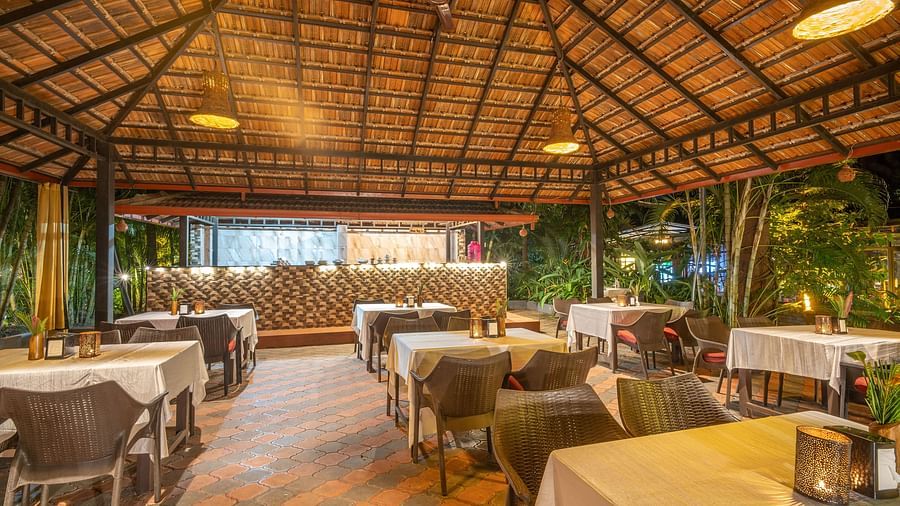 A dining hall with a seating area and a slanted roof at Parampara Resort & Spa, Kushalnagar.