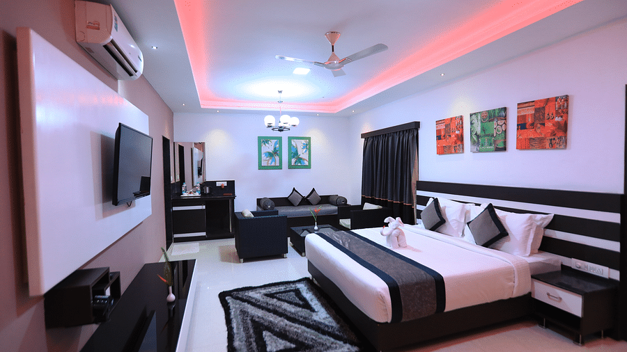 A room with a bed, a television, and a seating area at Parampara Resort & Spa, Kushalnagar.