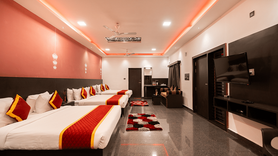 A room with four beds and a sitting area in the corner at Parampara Resort & Spa, Kushalnagar.