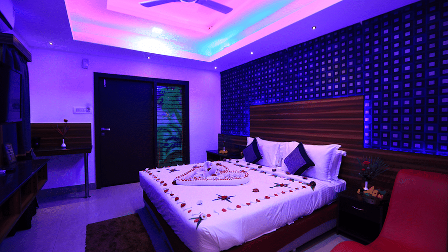 A dimly lit room with a bed decorated with petals and leaves at Parampara Resort & Spa, Kushalnagar.