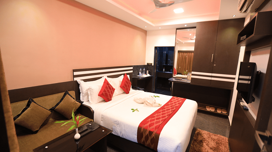 A room with a bed, a table, and a sofa beside it at Parampara Resort & Spa, Kushalnagar.