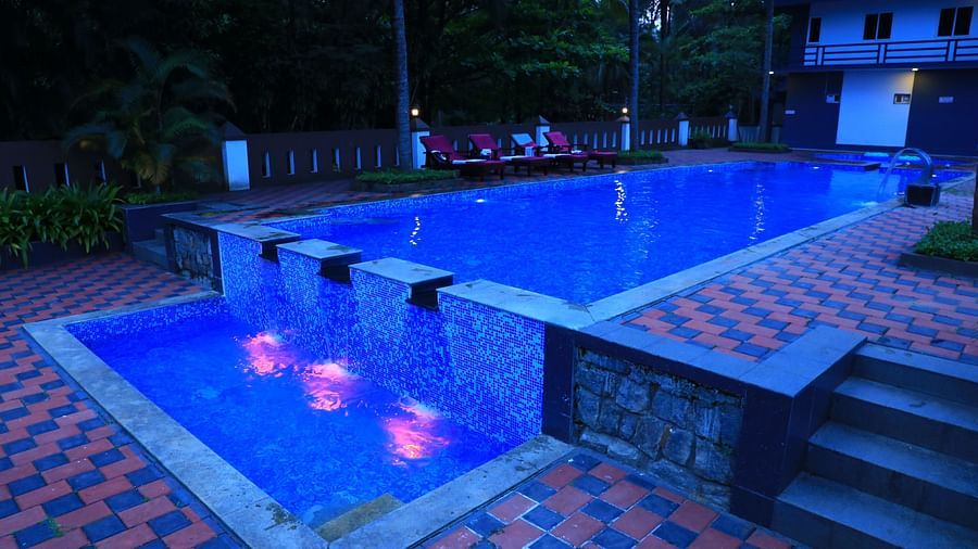 A swimming pool with stairs on the side at Parampara Resort & Spa, Kushalnagar.