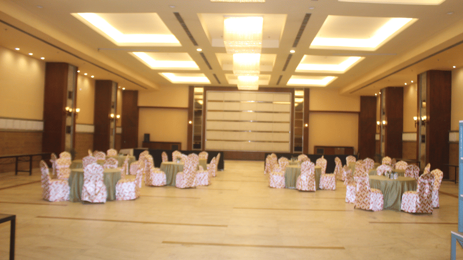Decorated chairs and tables arranged in a circular format in a banquet hall at Pipul Padmaja Premium Hotel & Convention.