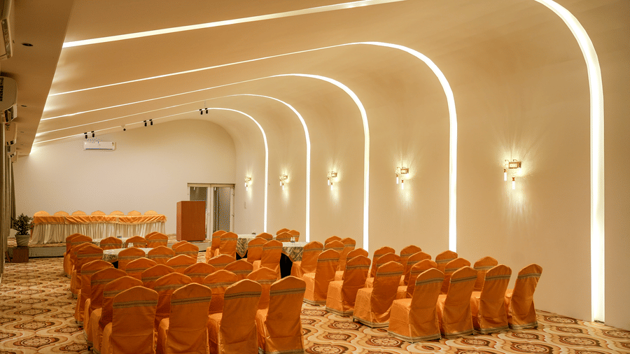 Banquet hall with orange-covered chairs arranged in rows at Pravasa Hotel, Kolhapur.