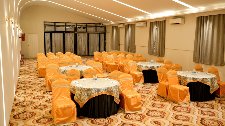 Banquet hall with tables and chairs arranged for dining at Pravasa Hotel, Kolhapur.