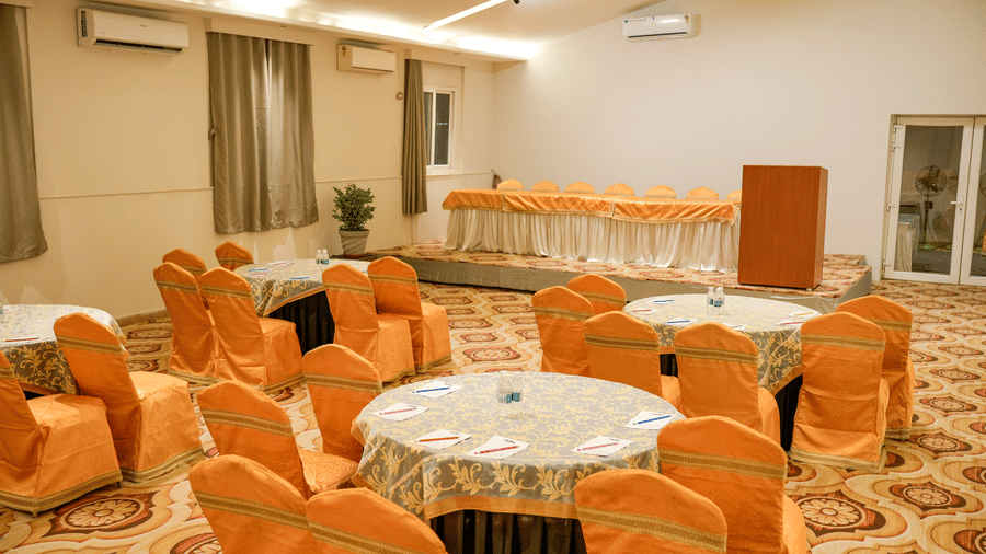 Banquet hall with round tables and chairs at Pravasa Hotel, Kolhapur.