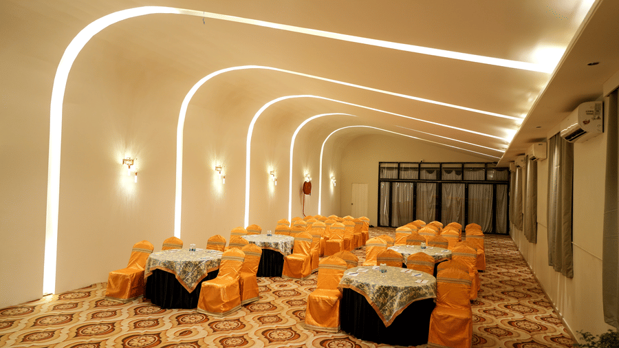 Banquet hall with dining tables and chairs at Pravasa Hotel, Kolhapur.