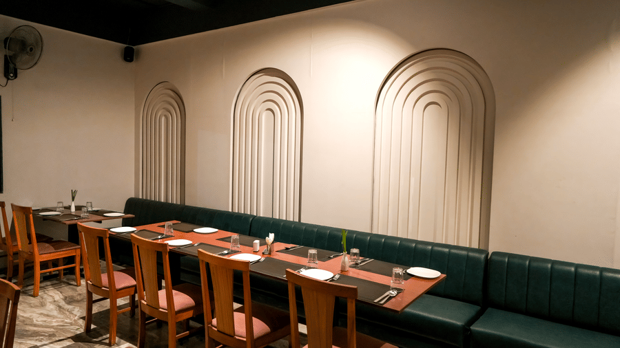  A comfortable dining booth with a dark green leather seat and decorative recessed white archways at Pravasa Hotel, Kolhapur. 