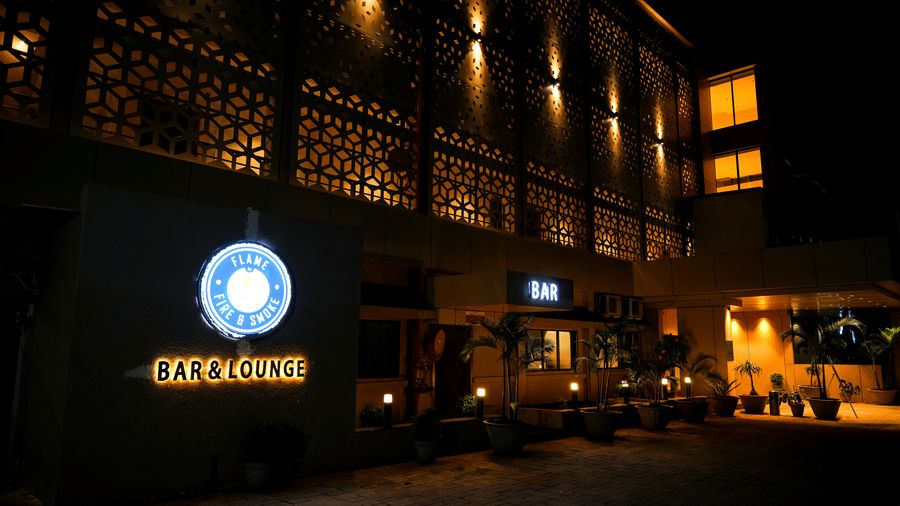 The striking exterior facade of Pravasa Hotel, Kolhapur, is illuminated at night, highlighting the modern geometric screen design.