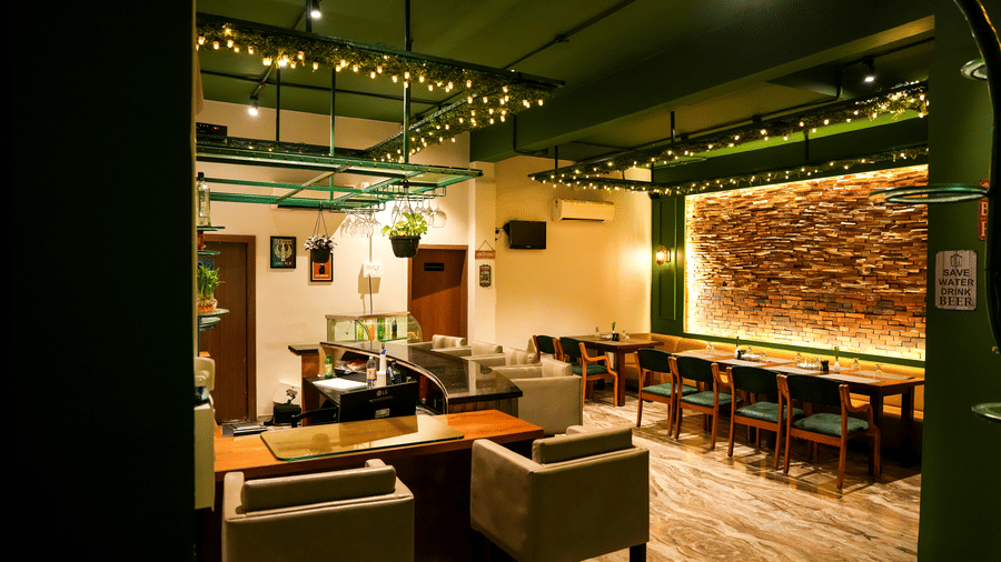  An overall view of the lounge and dining space with modern armchairs and a backlit brick feature wall at Pravasa Hotel, Kolhapur.